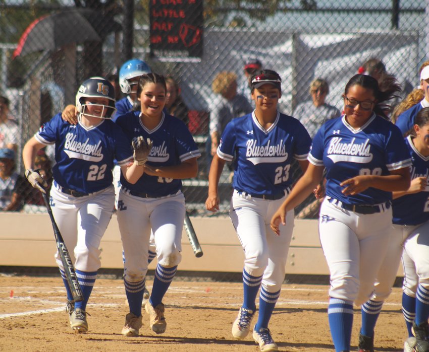 Fort Lupton's Reagan Mewbourne, far left, gets the hero's welcome from teammate Rozzie Mendoza, second from left, Areliana Bravo (9) and Desiree Floyd (99) after Mewbourne's first-inning home run against Strasburg at the state 3A softball tournament.